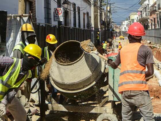 Betoneira sendo abastecida por operários numa obra