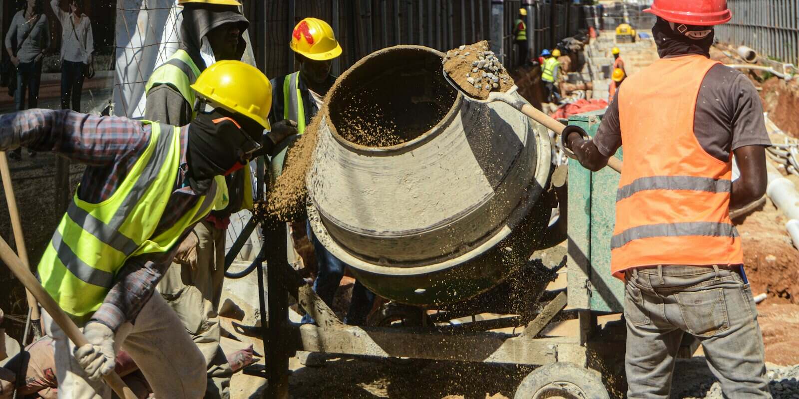 Betoneira sendo abastecida por operários numa obra