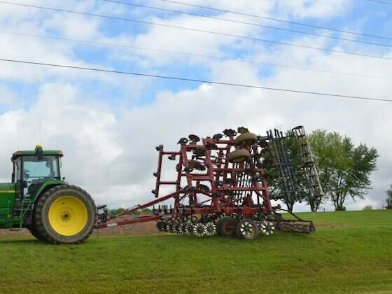 Trator com grade agrícola acoplada em campo verde