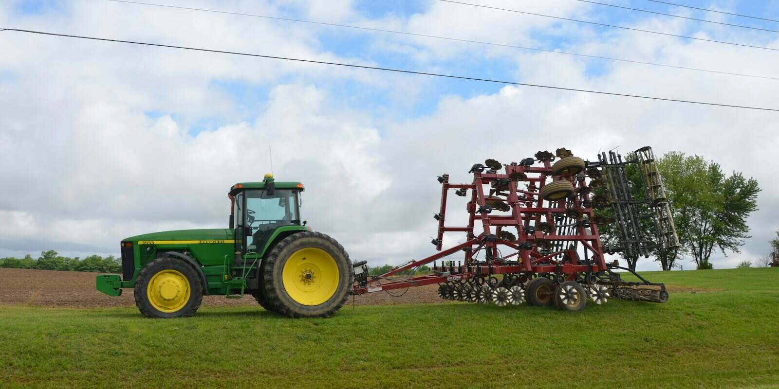Trator com grade agrícola acoplada em campo verde