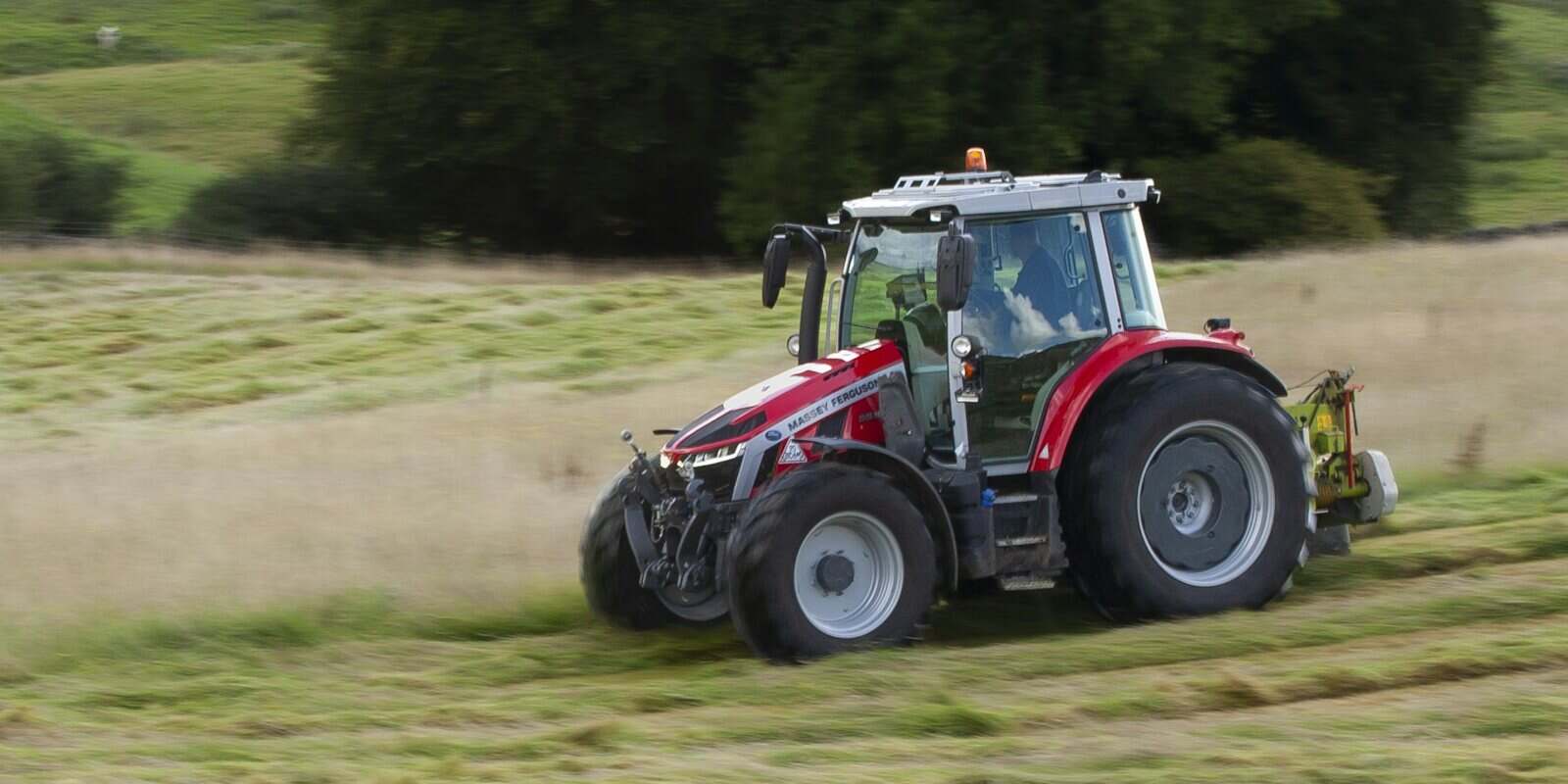 Trator com roçadeira cortando pasto alto